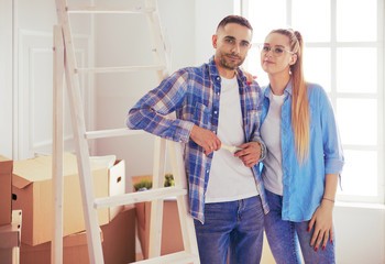 Obraz premium Smiling wife and husband standing in living room and discussing apartment interior, moving to new home