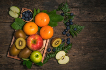Obraz na płótnie Canvas Fresh high vitamin c fruits, different fruits on old wooden table,The fresh apple, orange, blueberry, kiwi, Different raw fruits background.Healthy eating.
