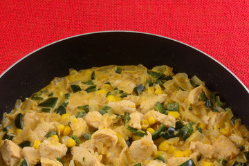 Cooking chicken chowder stew base with chopped chicken, corn, onion and poblano peppers in cream sauce in non stick frying pan