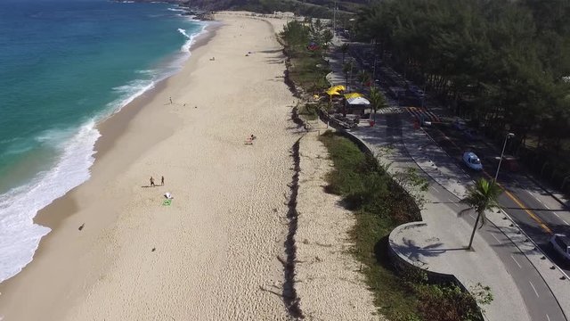 aerial footage of a beach with green mountain, nature and waves in a sunny day at brazil, rio de janeiro, recreio dos bandeirantes, macumba beach. Almost empty, without people. by drone dji phantom