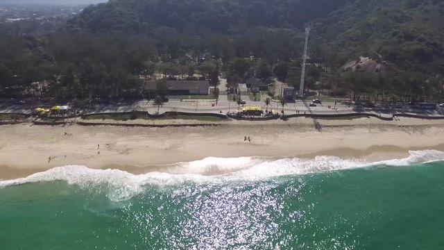 aerial footage zoom in of a beach with nature and waves in a sunny day at brazil, rio de janeiro, recreio dos bandeirantes, macumba. Almost empty, without people. by drone dji phantom