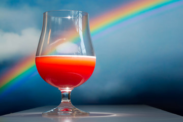 A bright red colored fruited sour ale craft beer against a rainbow background. All original elements.