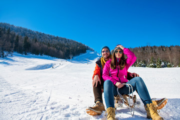 Fototapeta na wymiar Young happy couple sledding in winter at ski center