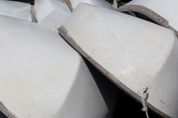 Obraz na płótnie Canvas Stacked small sailboats, white hulls with metal trim, horizontal aspect