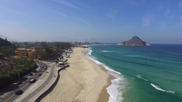 aerial footage of a beach with green mountain, nature and waves in a sunny day at brazil, rio de janeiro, recreio dos bandeirantes, Pedra do Pontal. Almost empty, without people. by drone dji phantom
