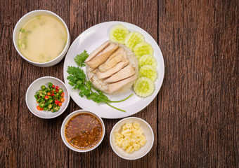 Steamed chicken rice with chicken soup, Hainanese chicken rice on a wooden background,