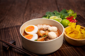 Spicy Noodles with Egg, fish ball and minced pork, Spicy Pork noodle with Spicy soup on wood background.
