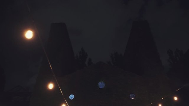 Feston illumination near the old stone building and lightning on the dark sky at the night
