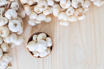 Garlics in wooden bowl with garlics on wooden table with copy space..
