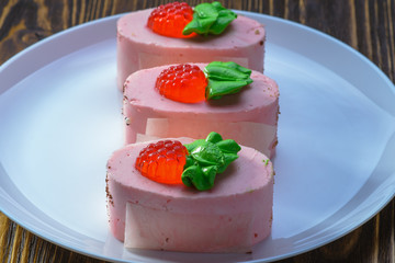 three tender pink cakes with red berries on a white dish