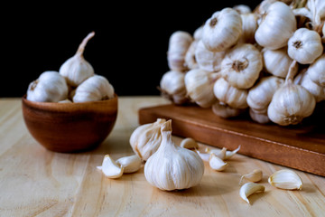 Closeup of Garlic bulb. Garlic bulbs in wooden bowl and Garlic cloves on wooden table on black background..