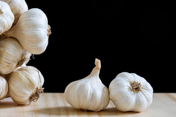 Garlic bulbs on wooden table on black background..