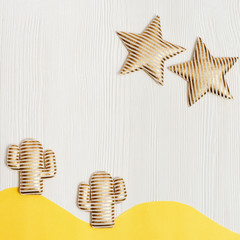 Summer composition with soft toy, two golden cactus and bright stars in desert on white wooden background. Creative summer concept.