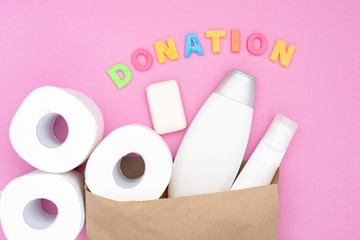 Food donation for the needy on a pink background top view. White toilet paper and hygiene products