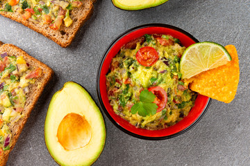 Bowl with guacamole made of ripe avocados on gray stone. Local Food Still Life.