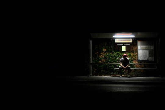 Man Waiting At Bus Stop During Night