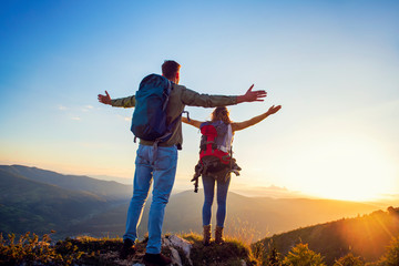Couple with raised arms holding hands and looking at sunset