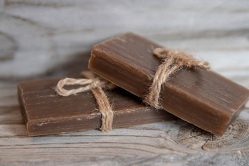 Two pieces of handmade soap tied with jute rope, vintage wooden background.
