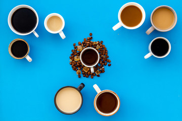 Cups of hot drinks on blue desk top view