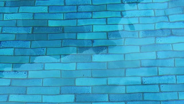 Top view of swimming pool water surface & underwater blue brick wall with calm ripple & waves slowly moved by wind in tropical summer or spring morning sunlight & sun rays at resort hotel or apartment