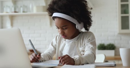 Afro american kid girl school pupil wearing headphones studying online from home watching web class lesson or listening tutor by video call elearning on pandemic isolation. Children remote education. - Powered by Adobe