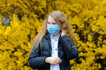 Portrait of sad caucasian child in face mask on closed playground outdoor. Coronavirus social distance quarantine.