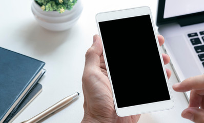 Man hand holding blank screen smartphone, top view.