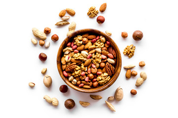 Mixed nuts in bowl on white background top-down