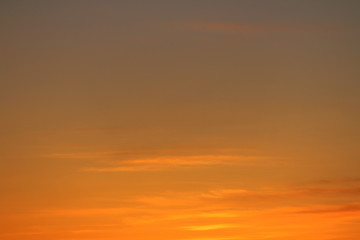 Sun below the horizon and clouds in the fiery dramatic orange sky at sunset or dawn backlit by the sun. Place for text and design.