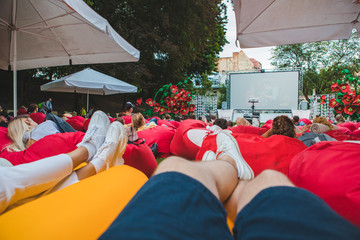 people at city public park watching movie at open air cinema