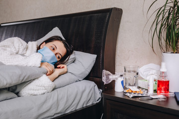 young sick woman in bed drinks pills