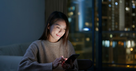 Woman use of mobile phone at home in the evening