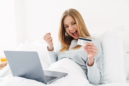 Image of excited woman holding credit card and making winner gesture