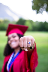 Multiethnic woman in her graduation cap and gown giving a fist pump. Selective focus on the fist. Way to go. Great Job Graduate!