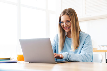 Image of cheerful charming woman smiling while working with laptop