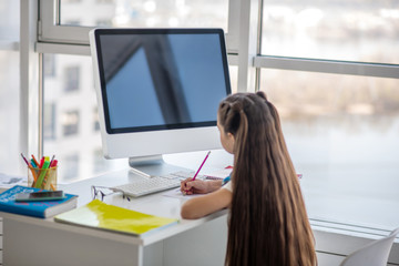 Dark-haired girl in white tshirt sitting at the table
