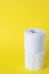 Rolls of white toilet paper on a yellow background. Copy space.