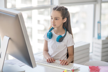 Long-haired girl in white tshirt looking at the computer