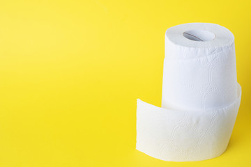 Rolls of white toilet paper on a yellow background. Copy space.