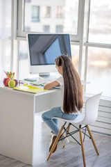 Long-haired teen sitting at the table and studying