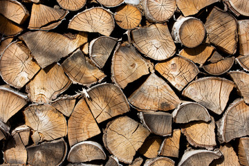 Fototapeta premium Birch firewood. Front image of firewood saw cuts. Firewood is dried and ready to kindle a fireplace. Cracked wood, texture is clearly visible. Horizontal photo, daylight