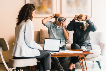 Excited mature people wearing VR glasses. Confident young woman introducing new product with help of virtual reality headsets. Technology concept