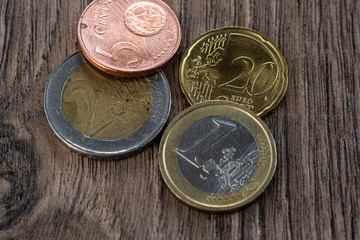 Euro coins and one hundred dollars on a wooden background