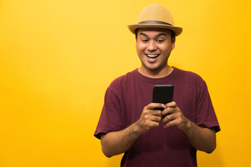Asian man happy with his smartphone on yellow background. young man using looking at smartphone.