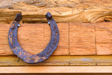 Metallic old horseshoe. Hanging over the entrance to the house. Strong rust and corrosion. Concept sign of good luck, amulet, mascot.