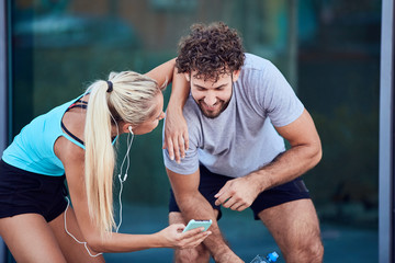 Modern couple making pause on the sidewalk during jogging / exercise.