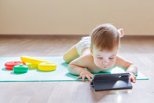 child chose to play with phone instead of toys. girl is watching cartoon, toys are lying around. Concept of advertising of equipment, phones, educational games, childhood, children's day, kindergarten
