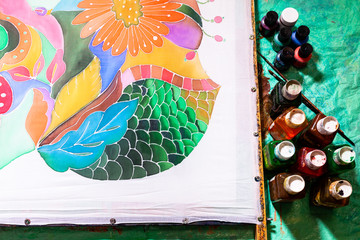 view of paints and silk canvas with floral batik