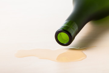 cognac bottle over spilled liquid on wooden board