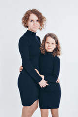 two happy girls are smiling on white background. Portrait of a mother and daughter embracing. The concept of family relations, friends, family day, mother's day